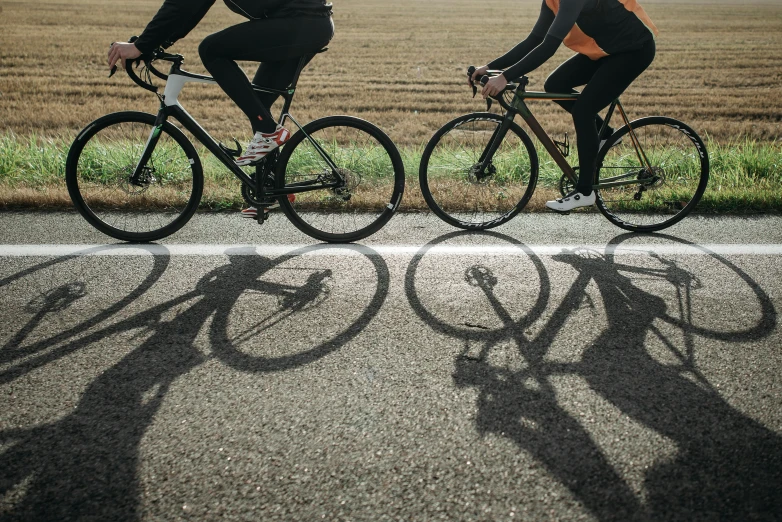 two men riding bikes together on a road