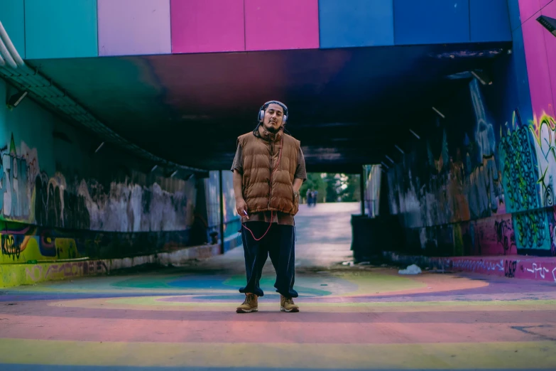 man standing underneath colorful bridge holding dog in hand