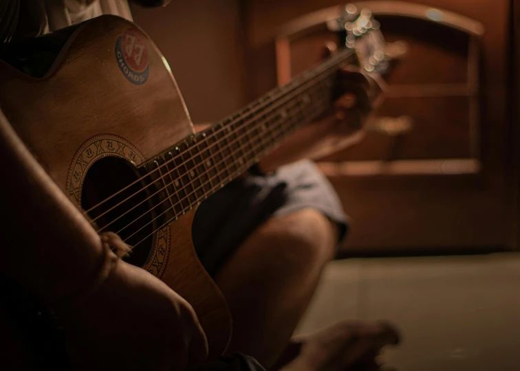 a man is holding a guitar in his lap