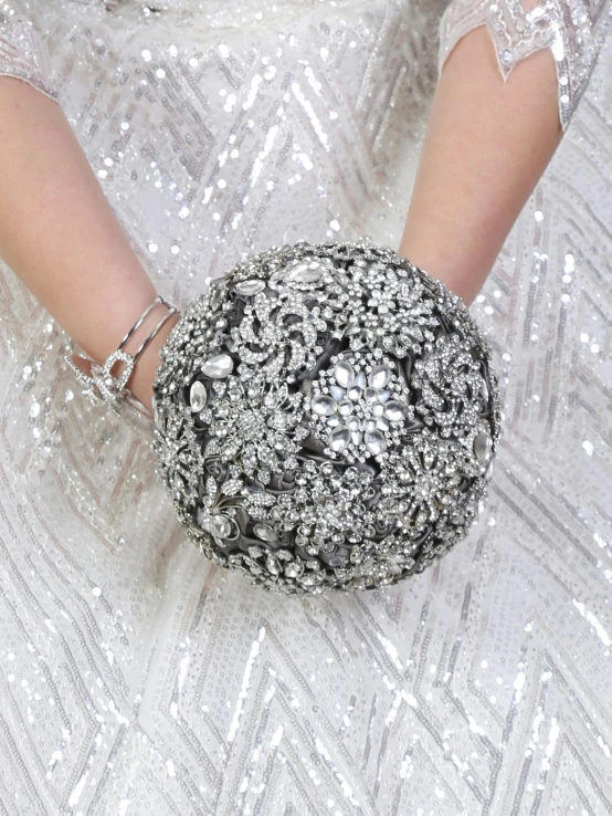 a close up po of a womans hand with white nails holding a silver ring ball