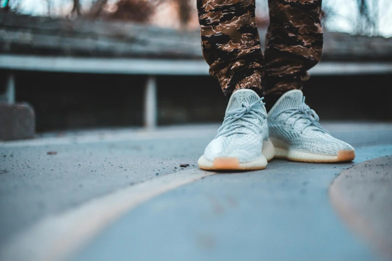 a person in camouflage pants and sneakers standing by some street