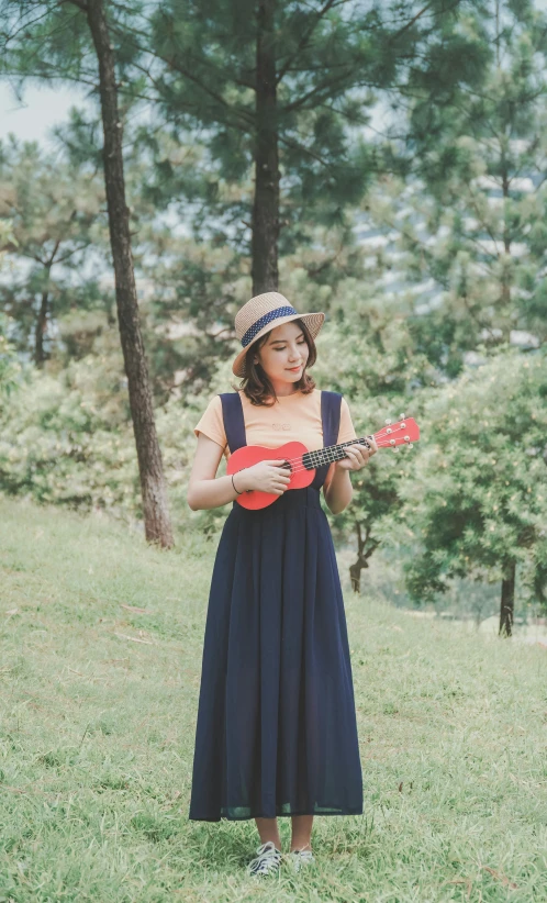 a young woman playing a ukulele in a field