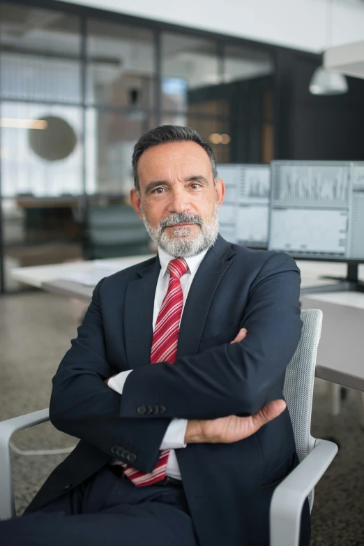 man in suit and tie sitting in a chair looking at the camera