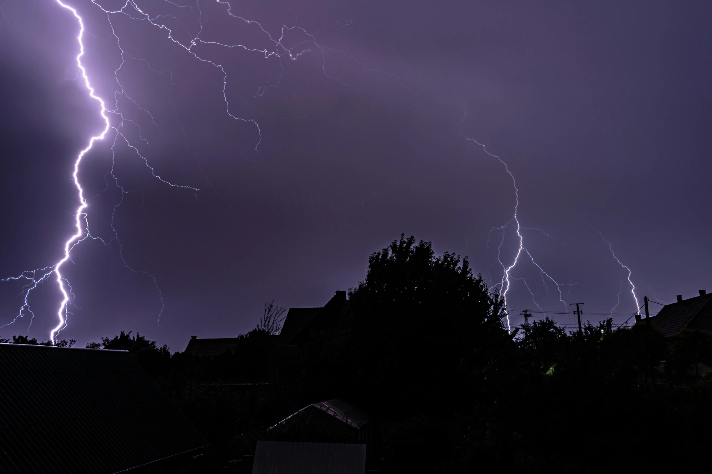 multiple bolts of lightning above some houses