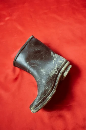 an old, dirty pair of boots sitting on a red carpet