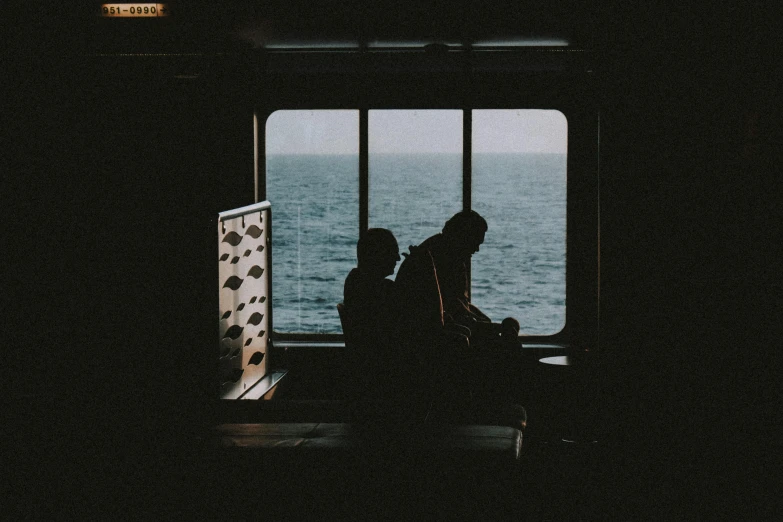 a couple sits beside each other near the ocean