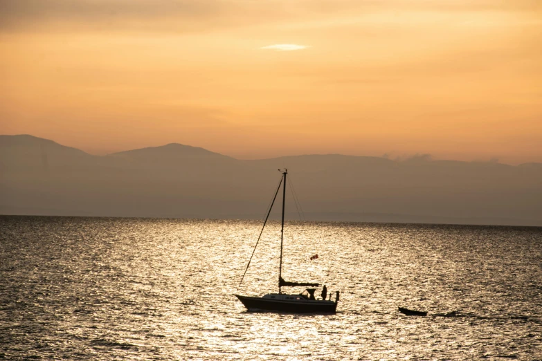 two boats in the water during sunset, while the sun sets