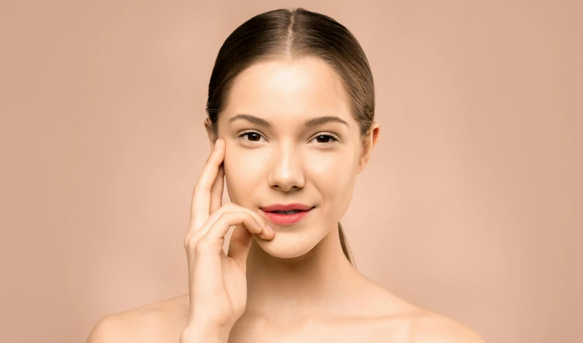 an attractive woman poses for the camera in front of a beige background