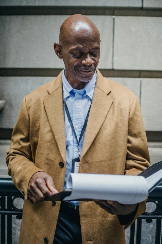 a man wearing a brown coat stands next to some large objects