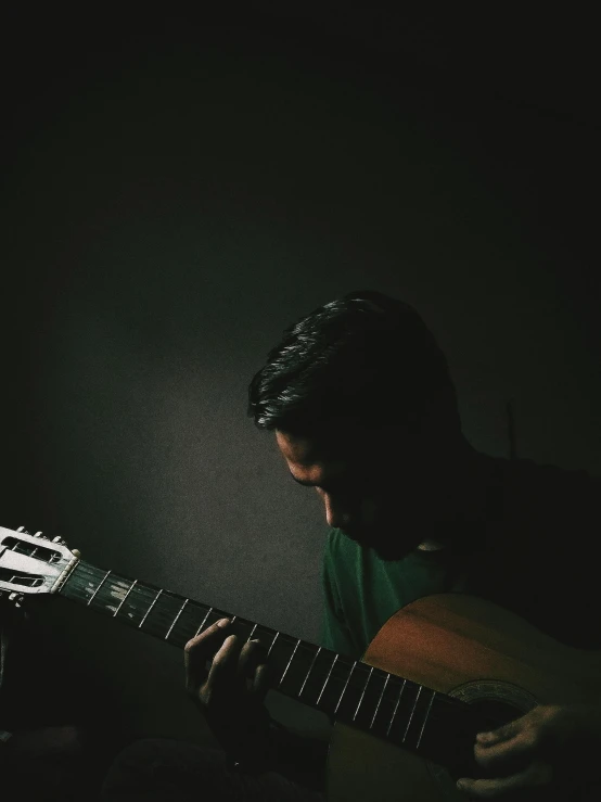 a man playing the guitar with dark lighting