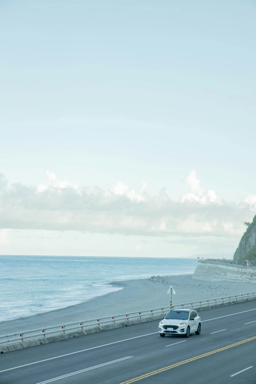 a small car traveling down the highway by the ocean