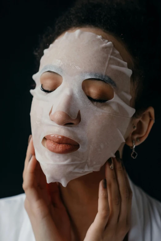 a woman in white is holding a sheet over her face