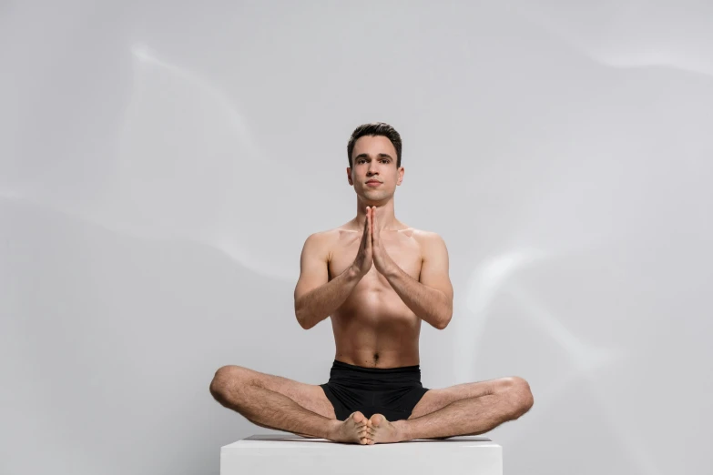 a man doing a yoga pose with his hands folded