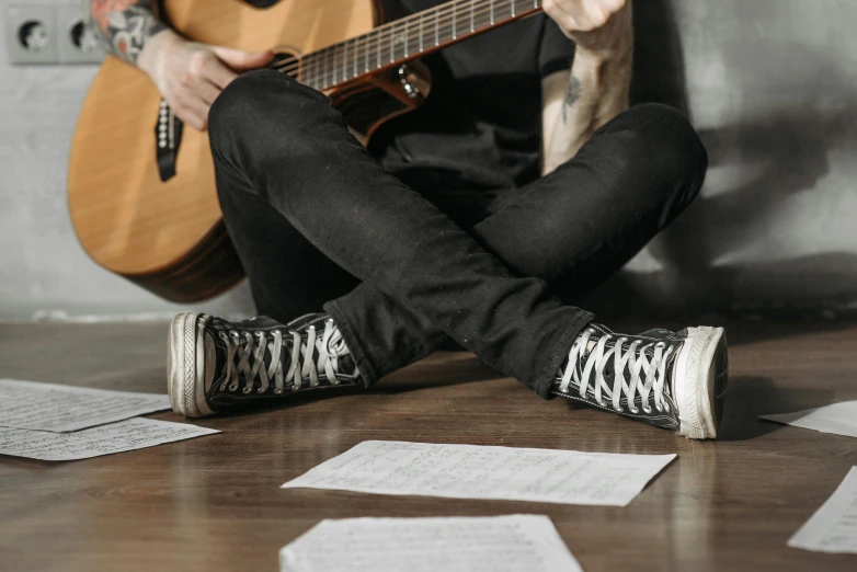 a person with a guitar is sitting on the floor