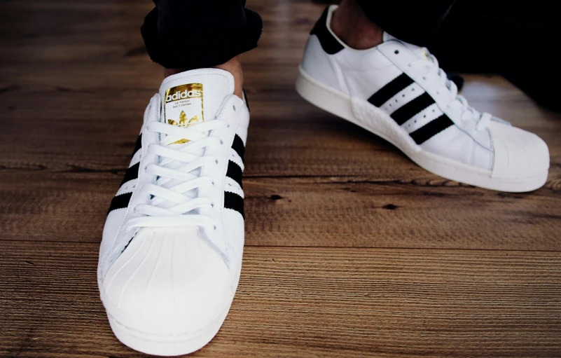 a close up of someone wearing adidas white and black shoes