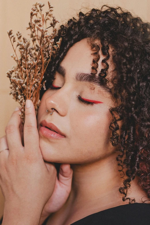 a woman with curly hair holding some flowers