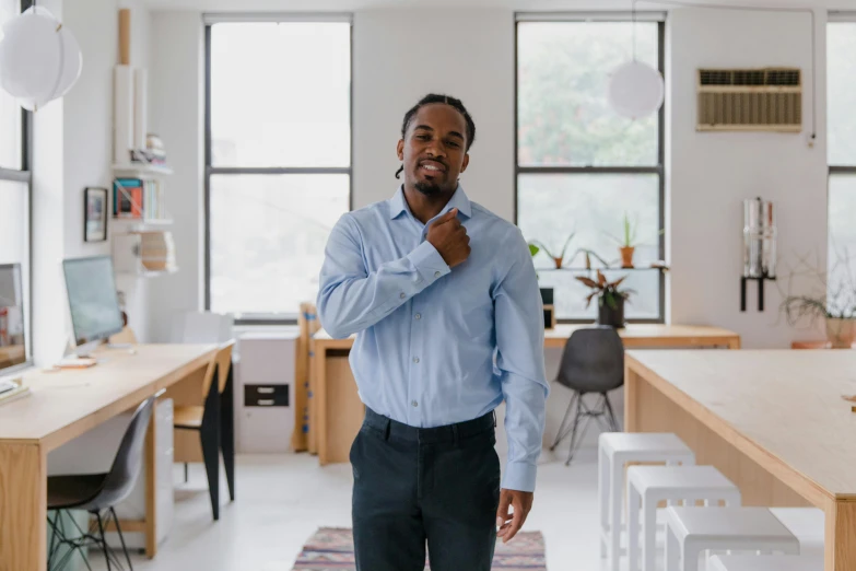 a man standing in an office wearing blue shirt and black pants