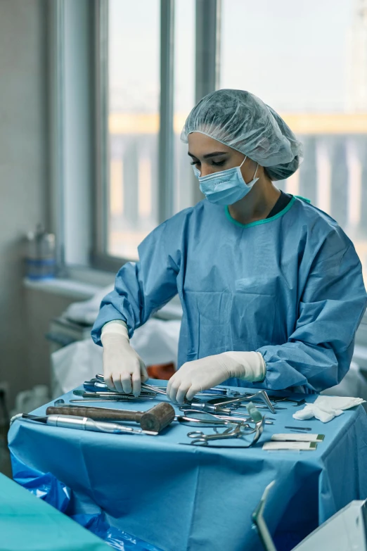 woman in blue gown and goggles operating equipment