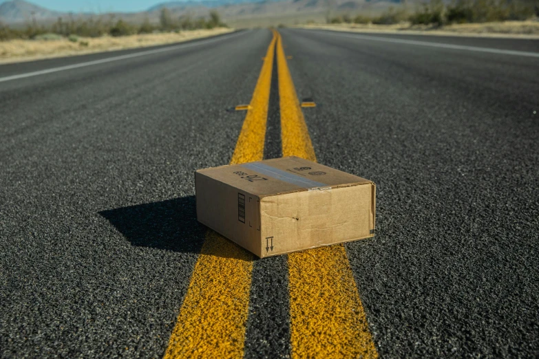 a brown box sitting on the middle of an empty road