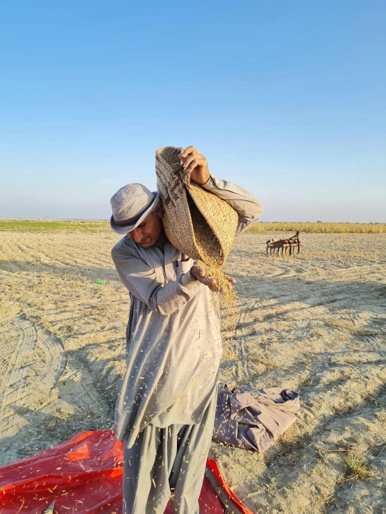 a man holding his hat over his head in a desert field