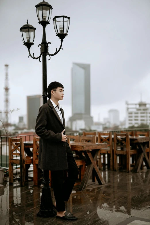 a woman standing under a street light in the rain