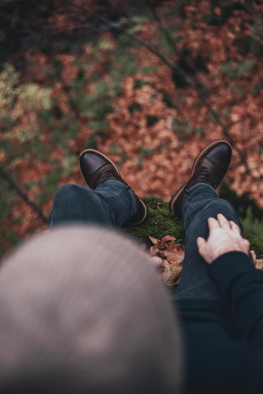 the person's feet are propped up on the ground next to leaves