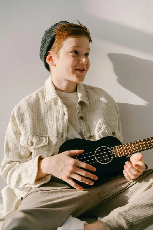 a boy sitting in the room with a ukulele