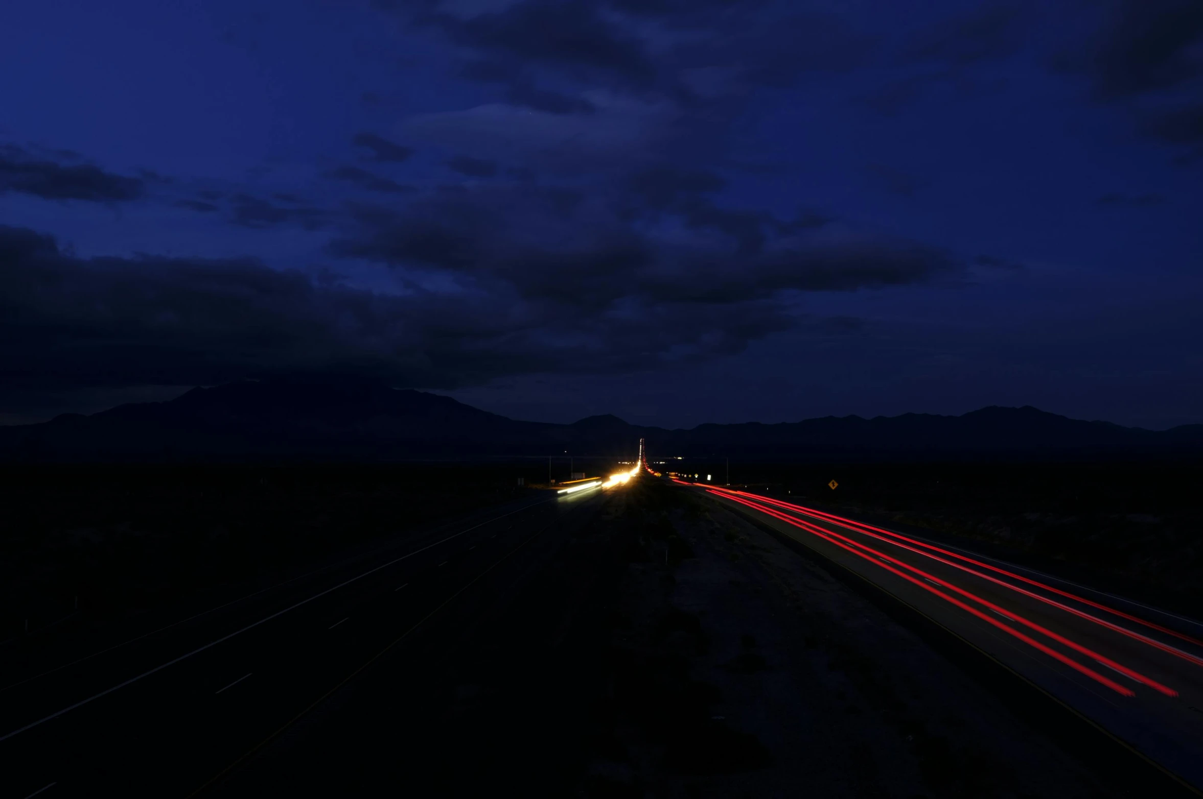 the night sky and the light streaks shine down on the road