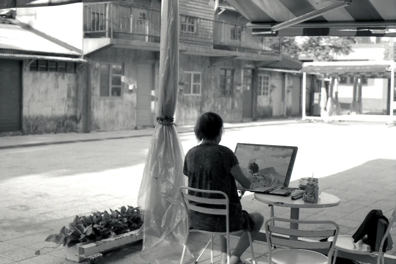 a young person at an outdoor table with paintings in front of him