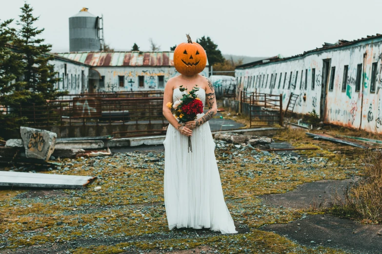 a person standing in an empty yard with a pumpkin head on their head