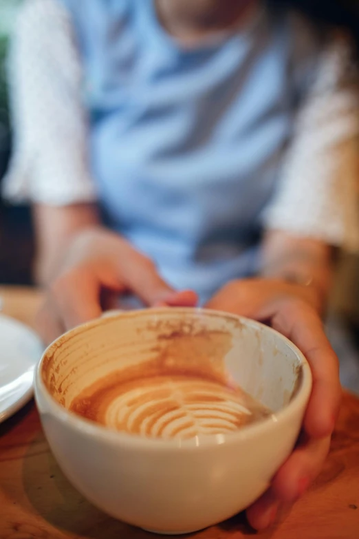 a cup of latte coffee is being held by someone