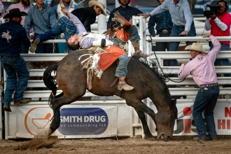 a man on a horse pulling a man off of the side of a bull