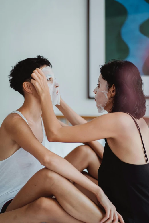 there are two woman that are both putting a face mask on