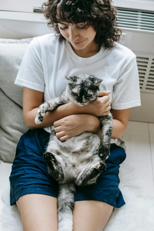 a girl sitting on a bed holding a cat