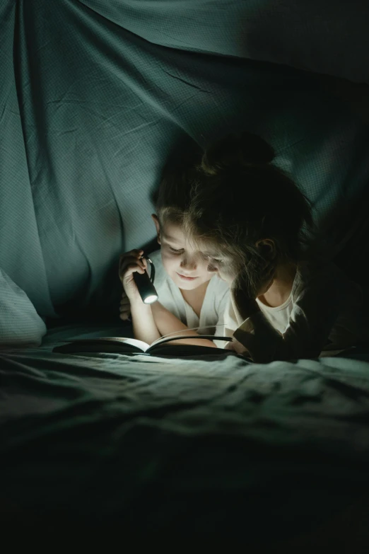 a girl laying down reading a book on her cellphone