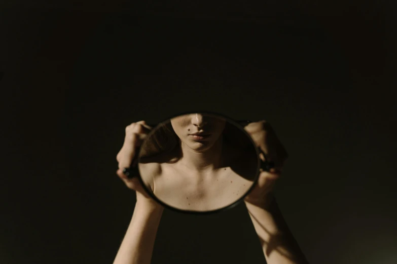 a woman holding a mirror and looking into it