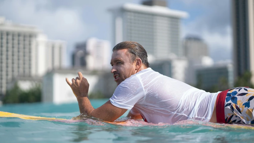 a man laying on top of a yellow surfboard in water