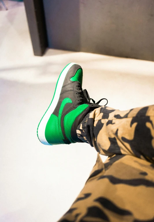 a person wearing green sneakers and camouflage pants