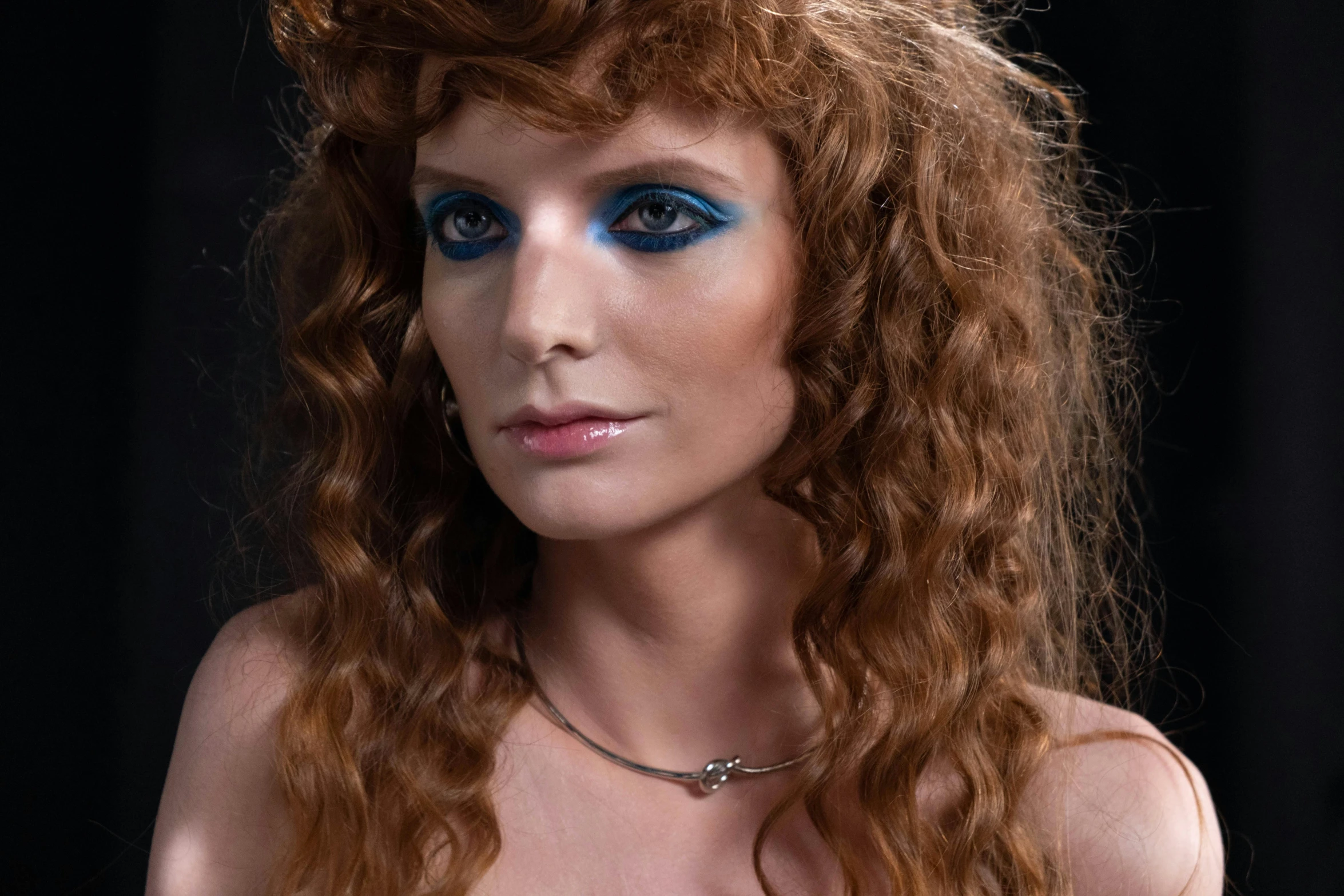 an old fashion po of a model with red hair and blue eye makeup