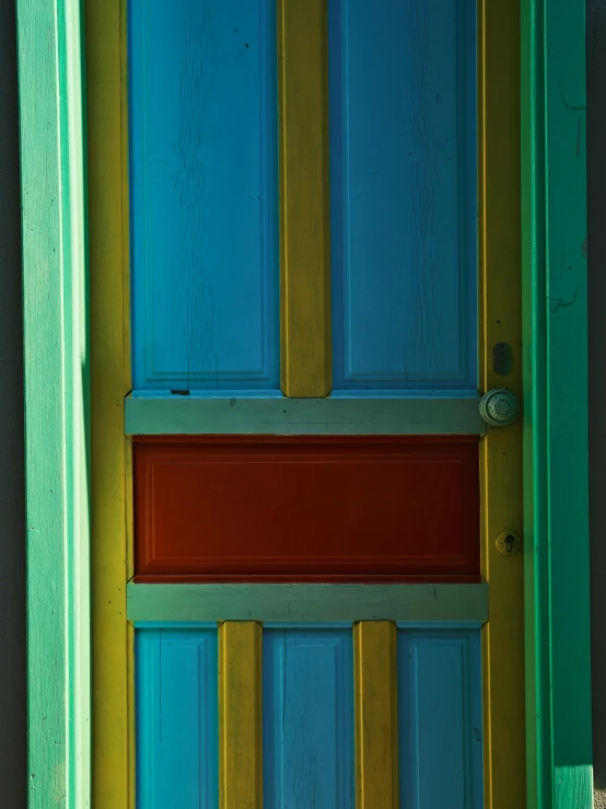 blue and yellow door and red trim on a gray wall