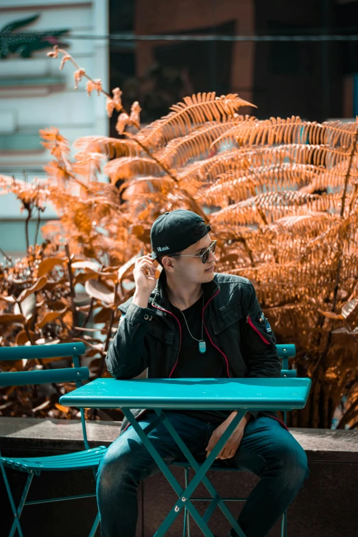 the man is sitting on a table by himself talking on his cell phone