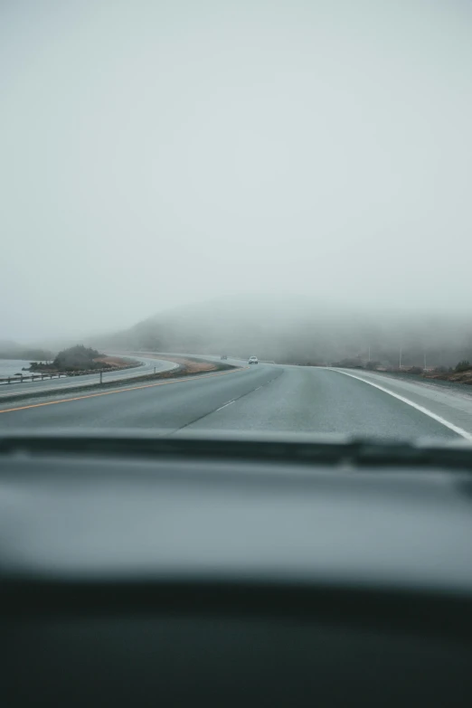 the view out a car window as the fog moves across a highway