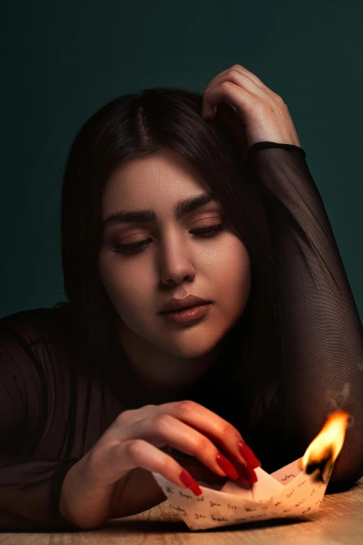 a woman sitting down holding a candle