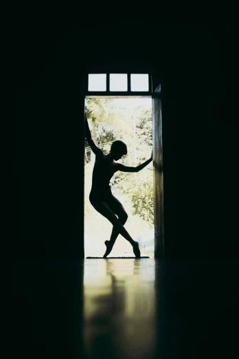 a woman standing on one leg and wearing all black doing a dance pose