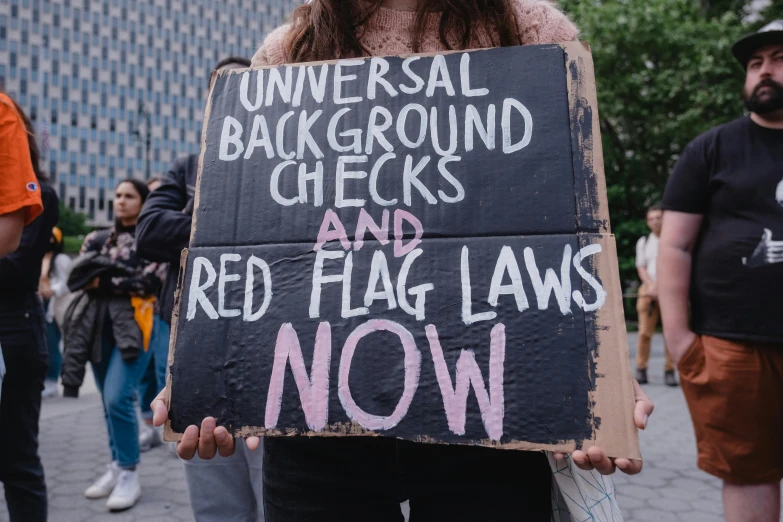 a protestor holds a sign protesting a university background check