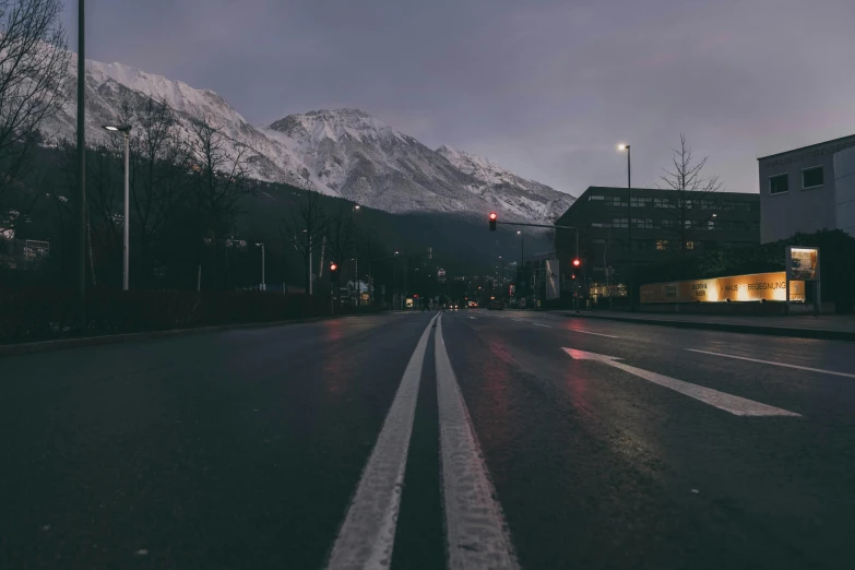 the mountains can be seen in the distance behind a street with a white line