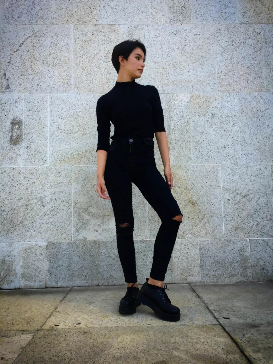 a woman standing on the sidewalk wearing a black outfit