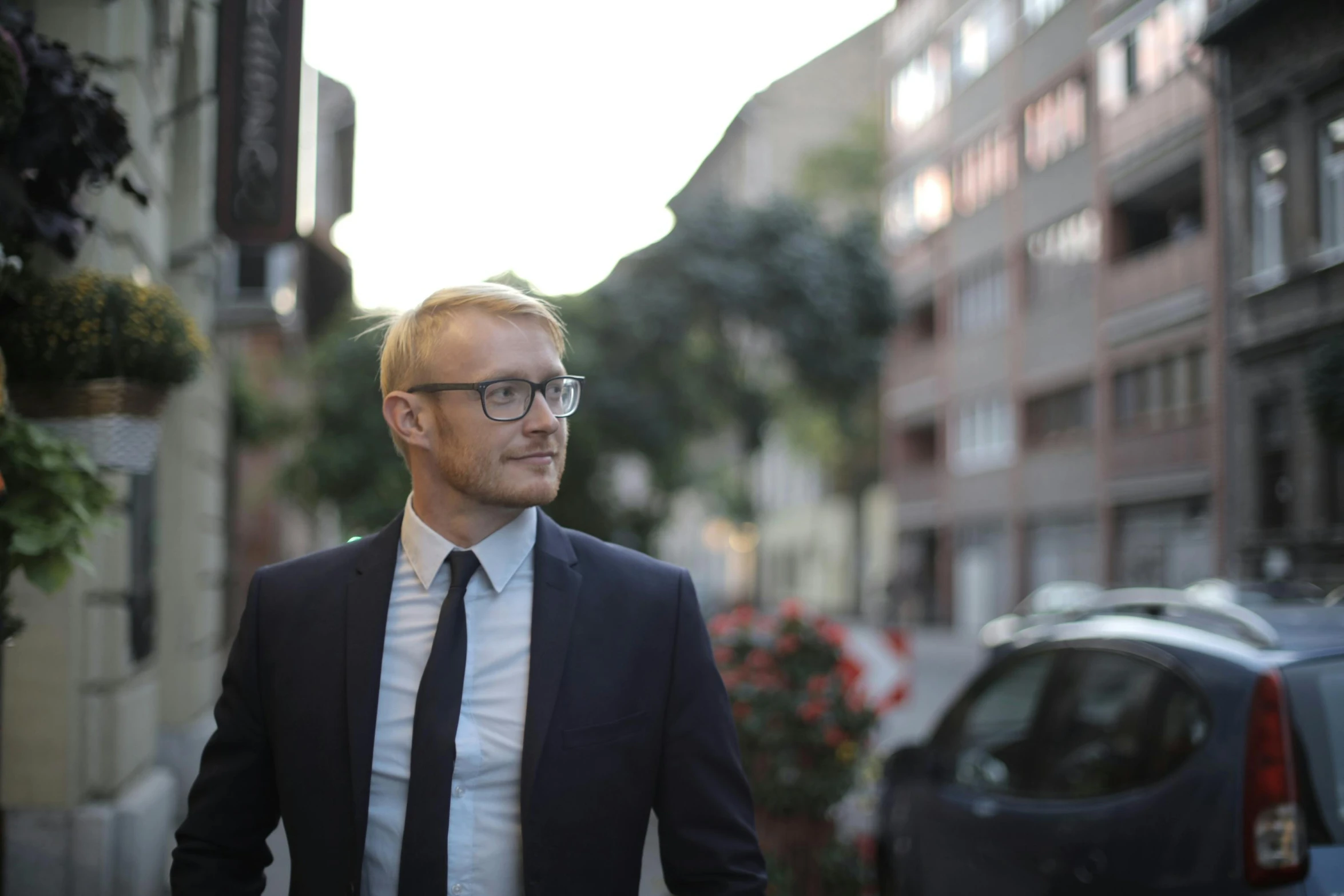 a young man wearing a suit and tie walking down the street