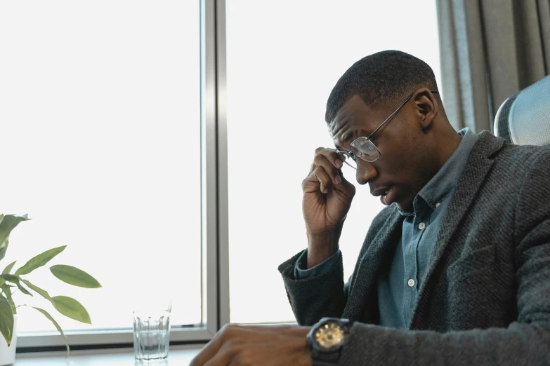 a man sitting at a desk in front of a computer monitor and writing