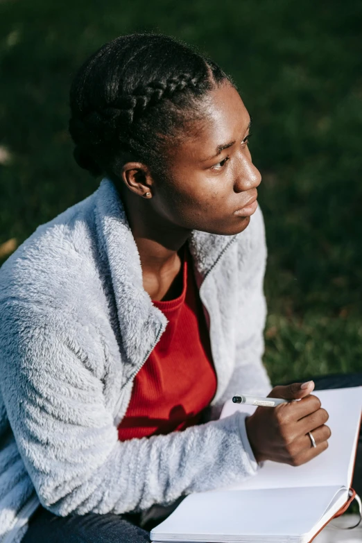 the young woman is writing on her notebook